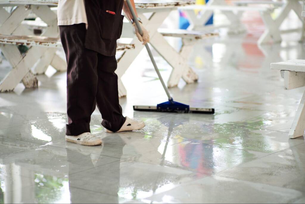 Floor care professional using a wiper to clean a wet indoor floor with precision and attention to detail