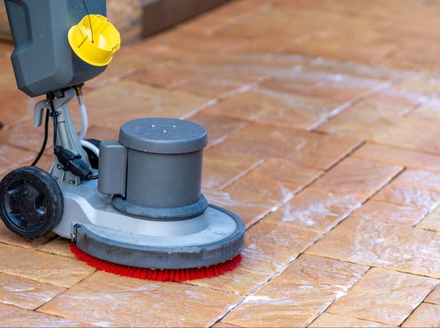 Professional floor care service cleaning a building’s stone pavements using a mechanical brush with water and detergent
