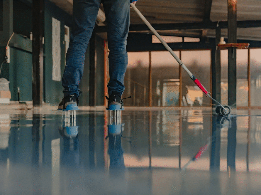 A worker applies a fresh coat of epoxy resin to a floor.