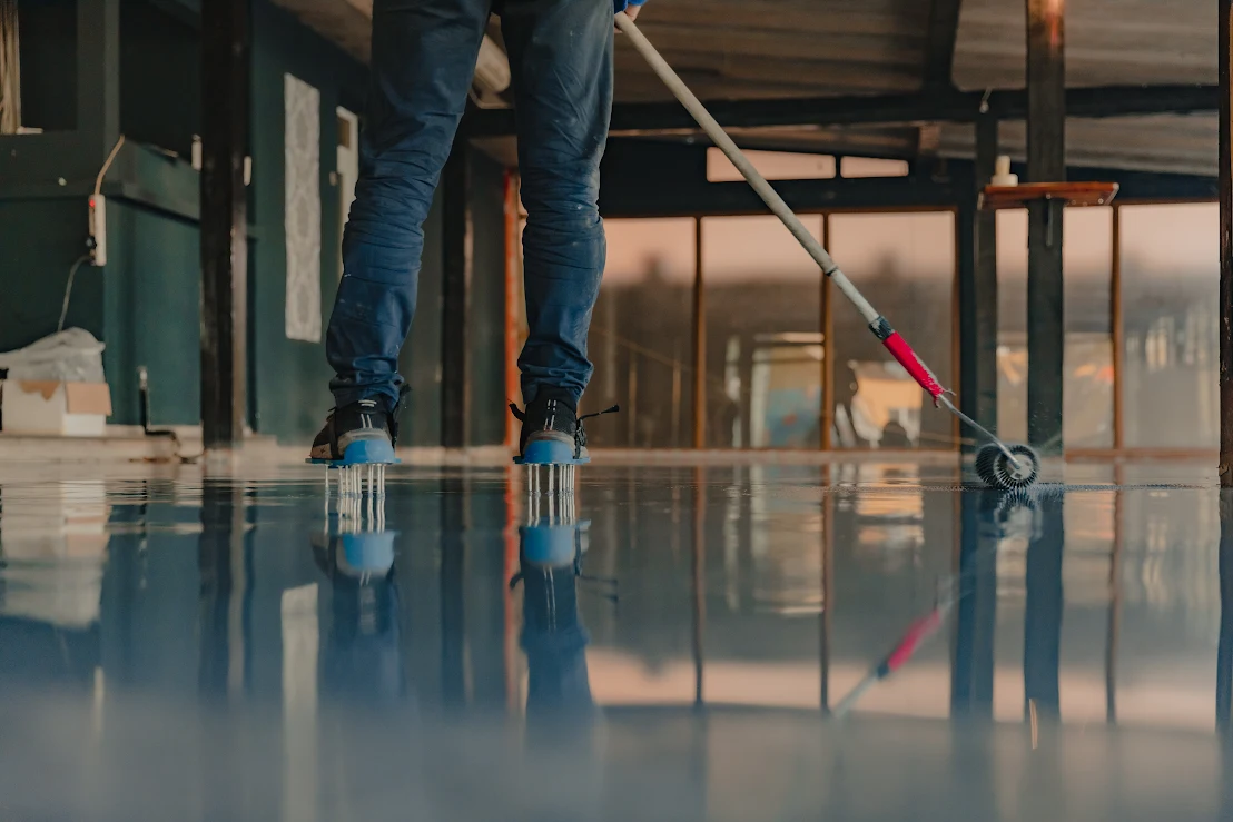 A worker applies a fresh coat of epoxy resin to a floor.