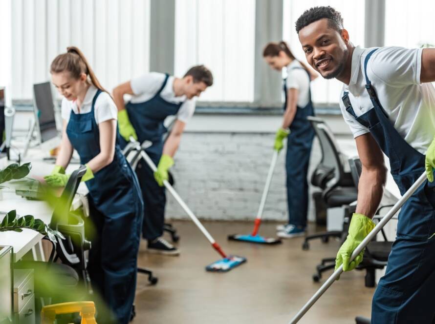 smiling multicultural cleaning team mopping office floors during a professional workplace cleaning service