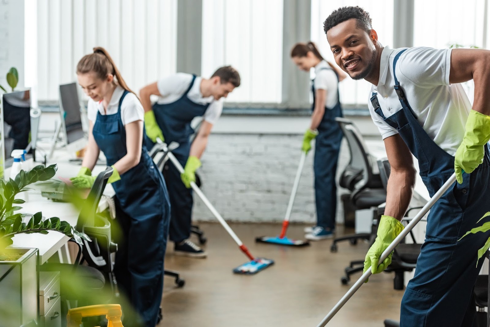 smiling multicultural cleaning team mopping office floors during a professional workplace cleaning service