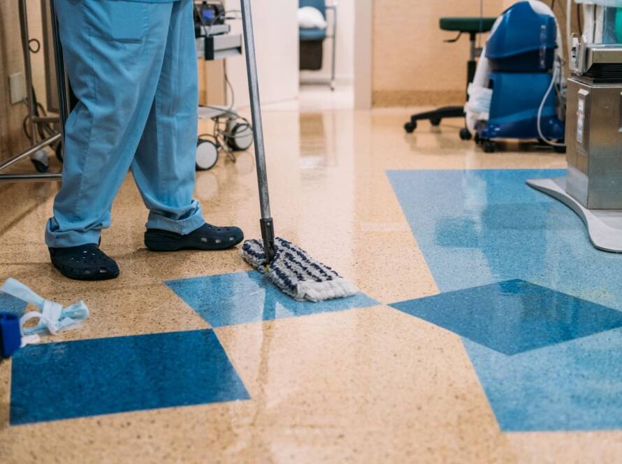 Detail of a cleaning technician in uniform sanitizing a hospital operating room